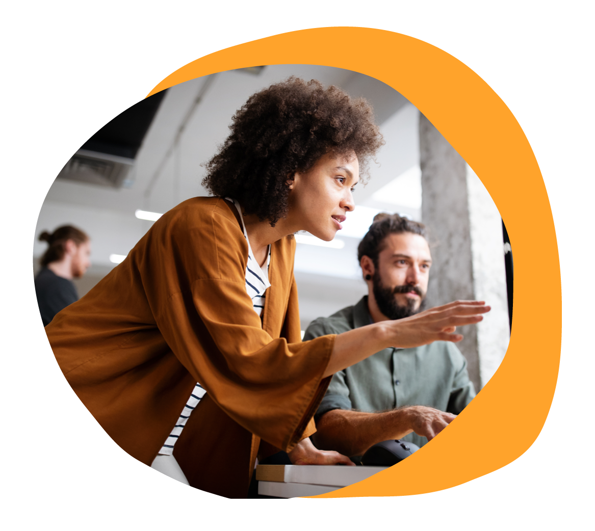 collaborative workspace with two coworkers discussing a project, one gesturing towards the screen, modern office setting, teamwork in an office, engaging discussion between colleagues, focused expressions