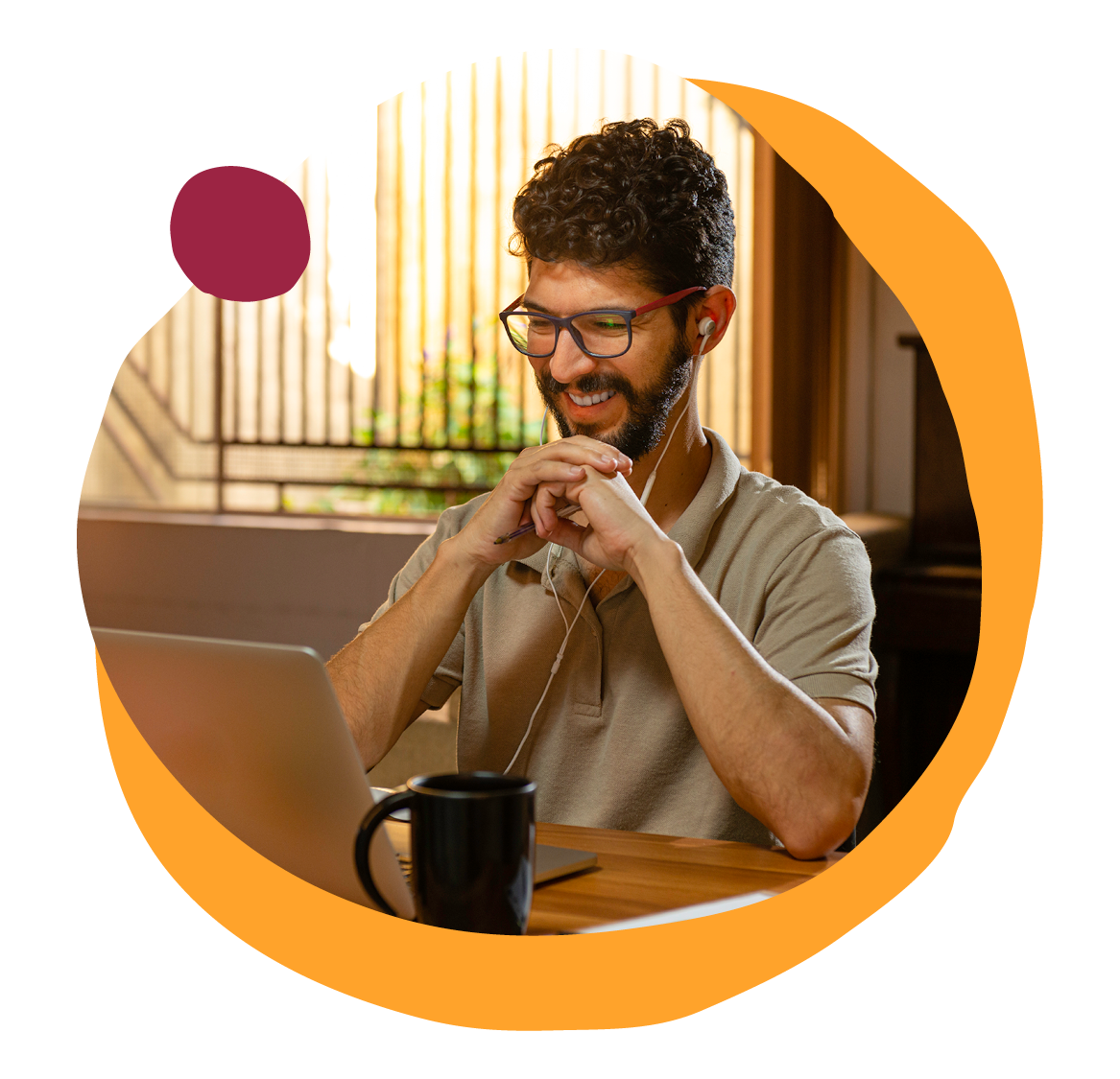 smiling man with glasses enjoying video call, home workspace with laptop and coffee mug, bright natural light
