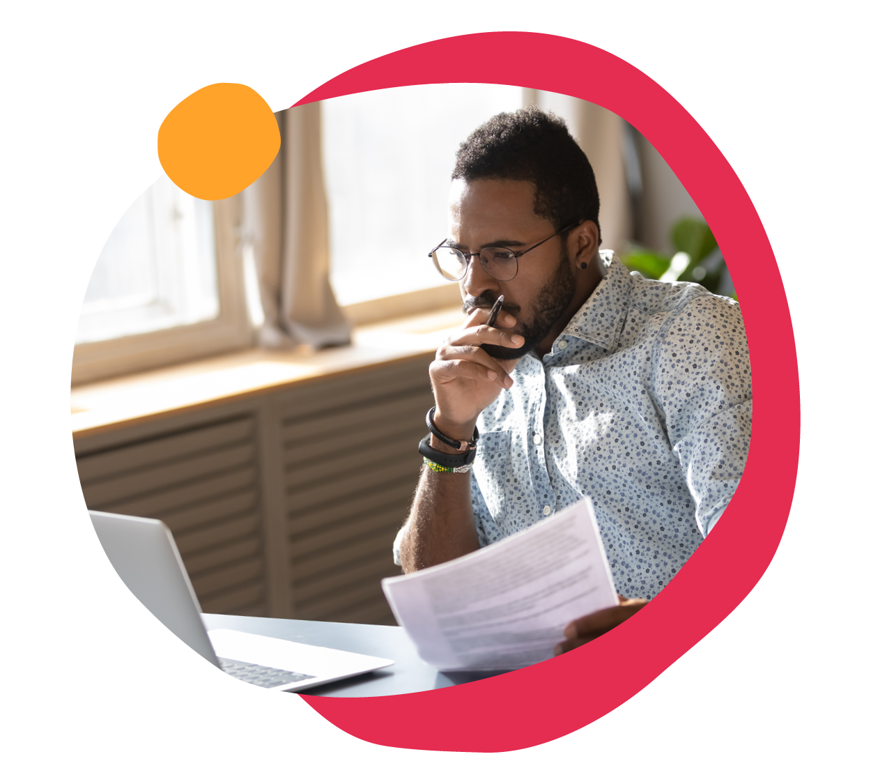 focused man analyzing documents, home office setting with laptop and natural light