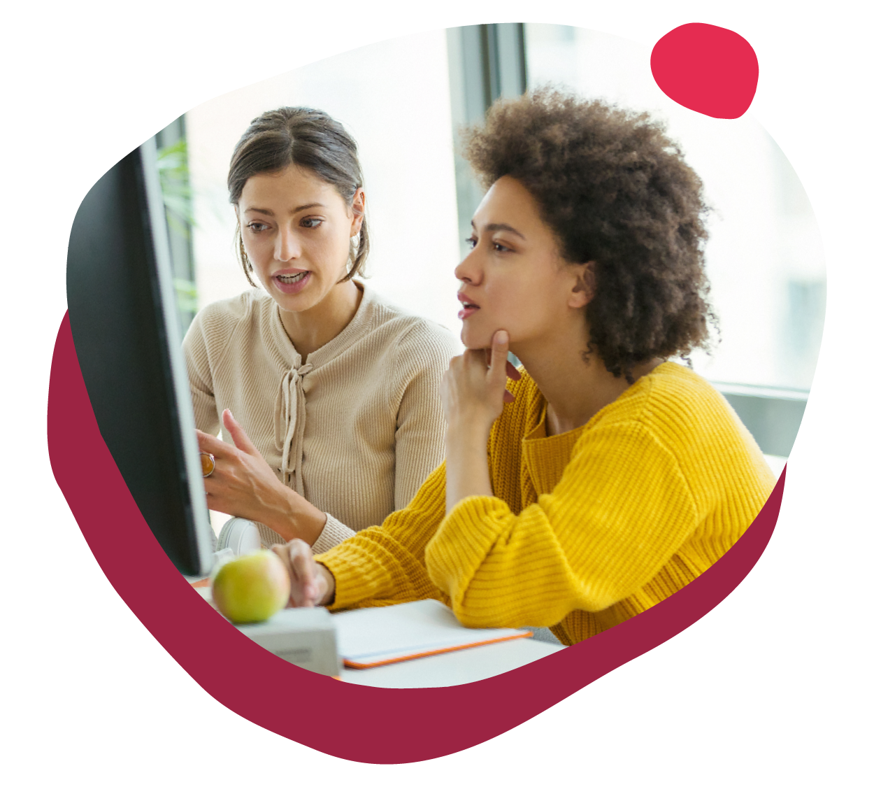 collaborative women discussing ideas at a computer workstation in a bright office, two women engaged in conversation and teamwork