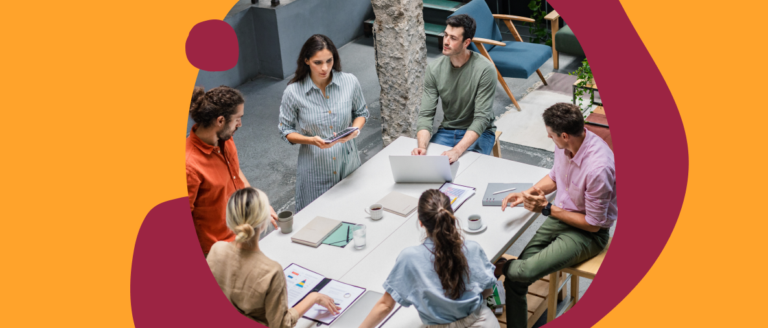 collaborative team meeting around a table with laptops, discussing ideas in a modern office space, diverse group brainstorming with digital devices