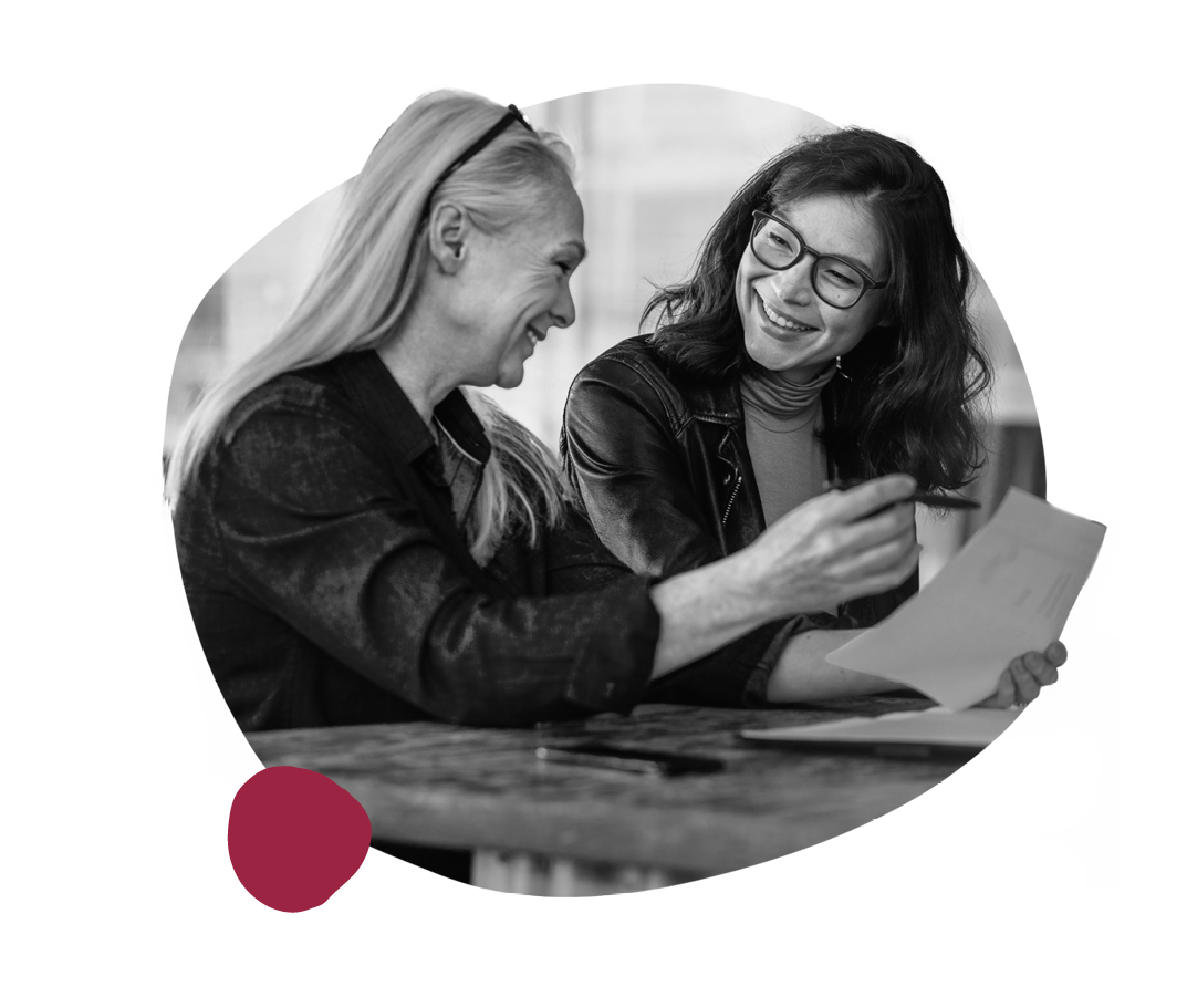smiling women engaged in discussion over documents, professional collaboration in a modern workspace