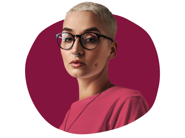 short-haired person in glasses wearing a pink shirt, highlighted against a burgundy background, stylish portrait with facial piercings