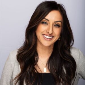 smiling woman with long dark hair, wearing a gray cardigan, on a light purple background, confident professional headshot image