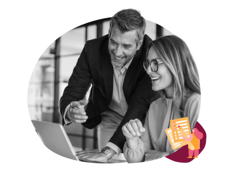 Two coworkers smiling and collaborating while looking at a laptop in an office setting.
